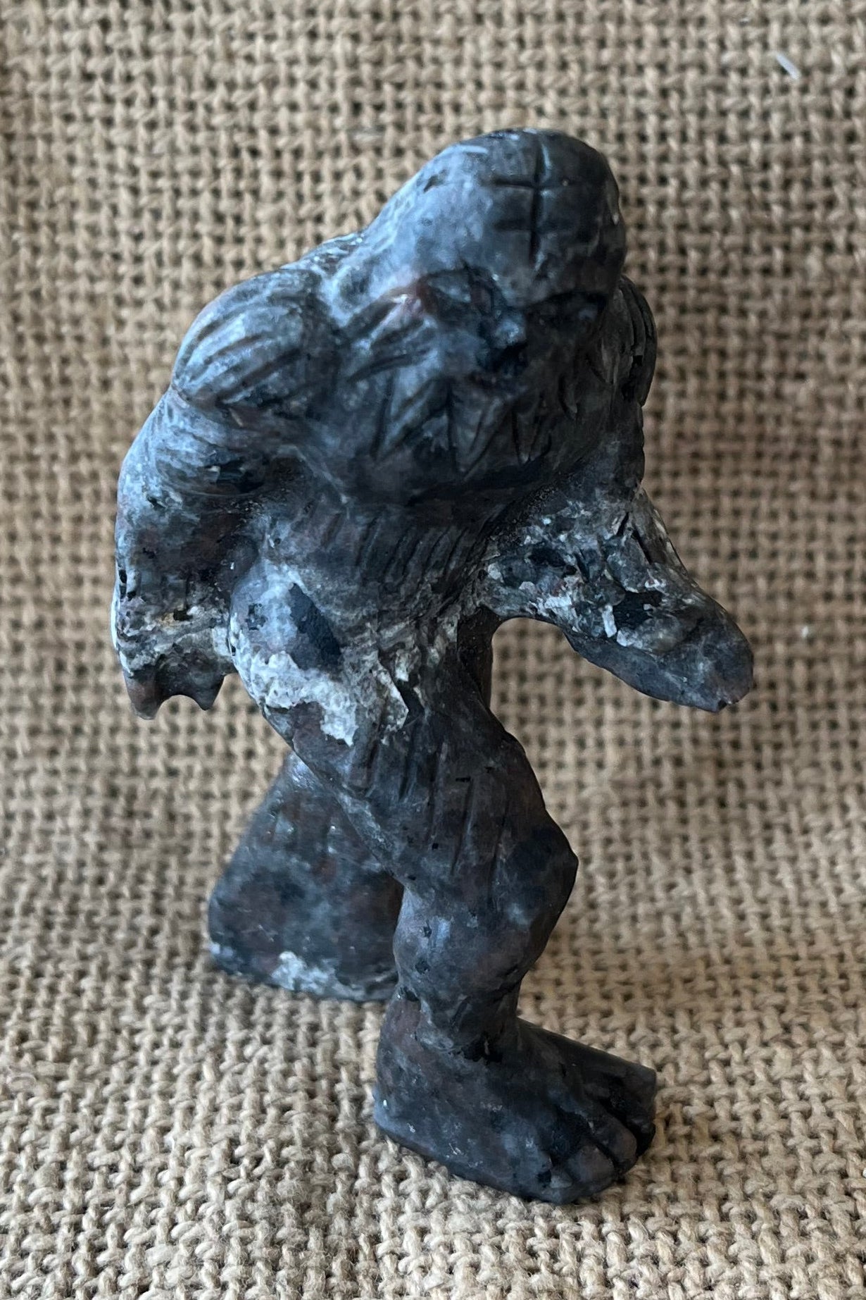 Gray black and tan crystal sasquatch on a tan textured background. 