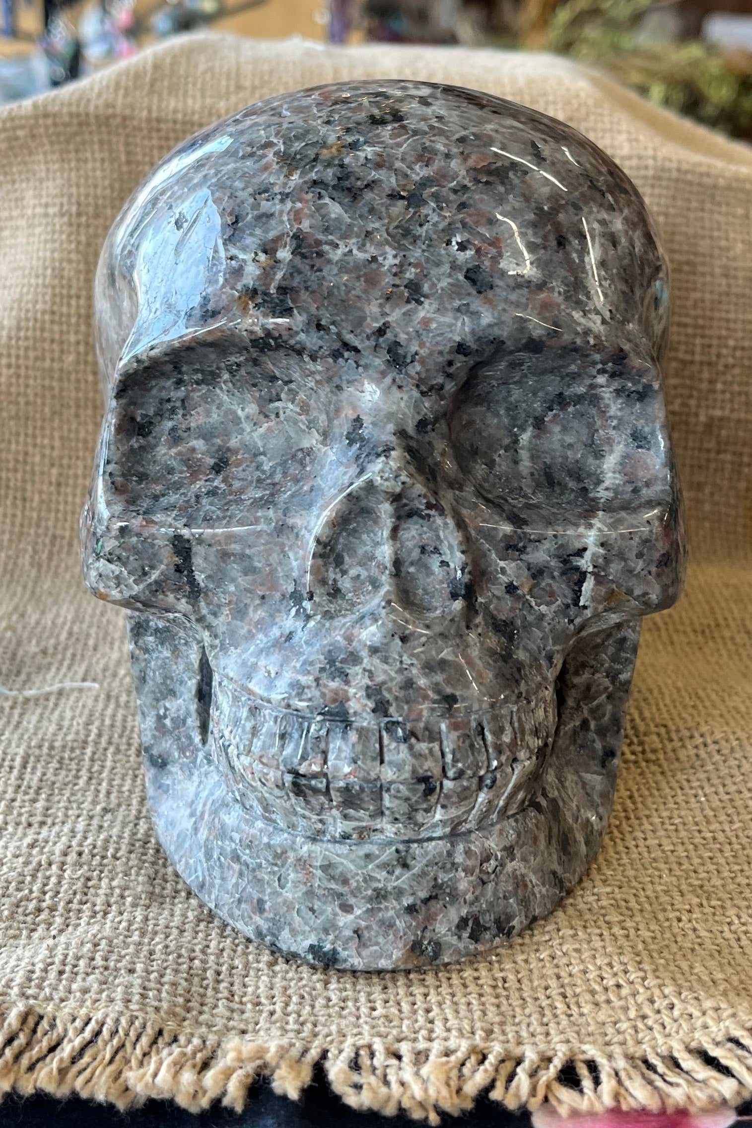 A gray and black patterned stone skull sits on a tan textured background.